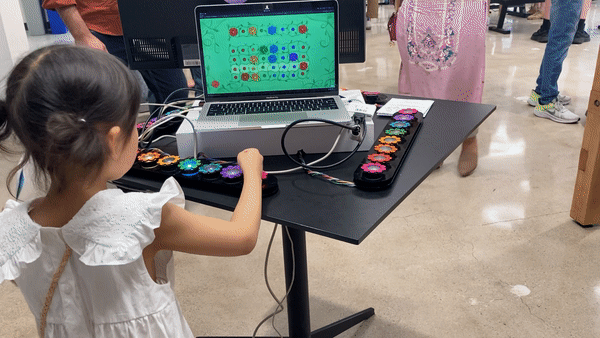 A child plays with a row of buttons, then moves around the interactive to play with the next row when it lights up.