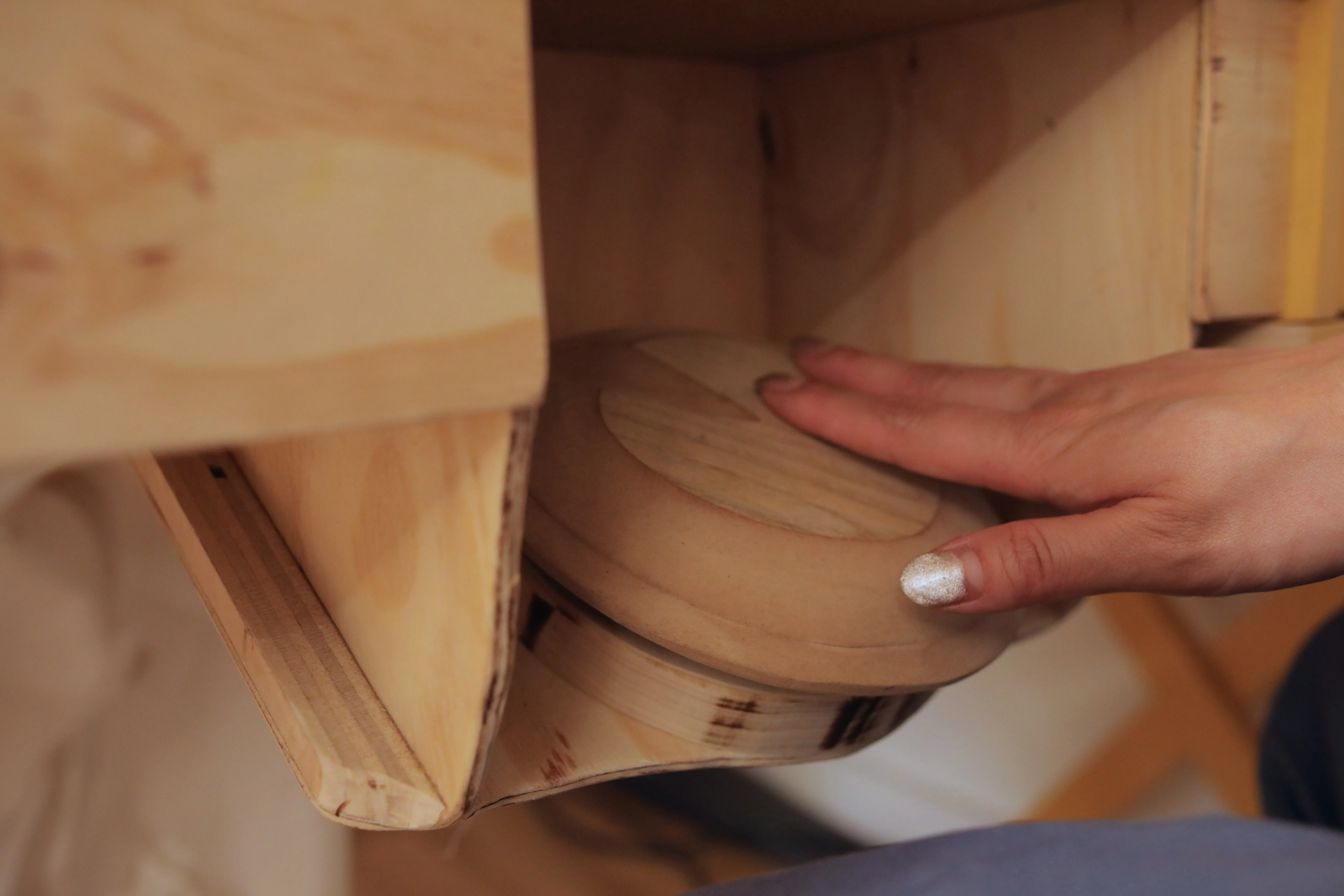 A hand spins a small wooden wheel