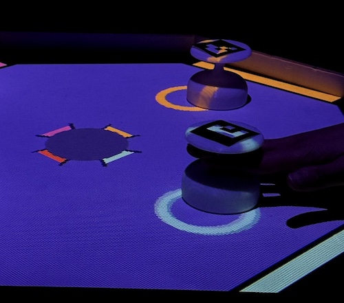 Controllers sit atop a projected playing space on a table